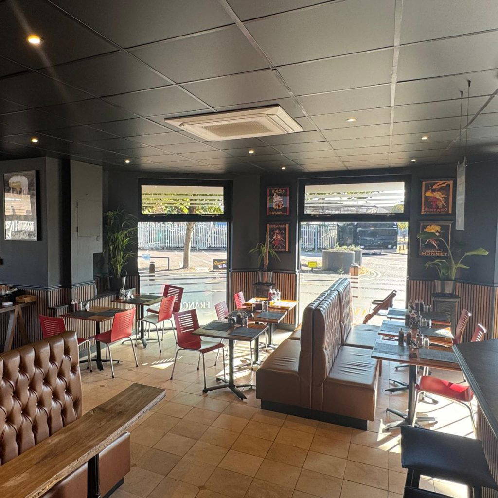 Photo of the interior of Francombs Diner. Banquette seating, wooden table and red chairs in a black interior.